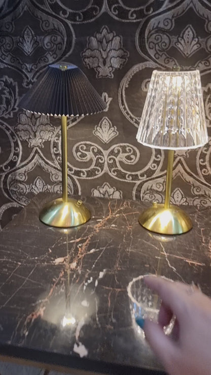 a table lamp with a pleated, cream-colored shade and a brass-toned base and stem.