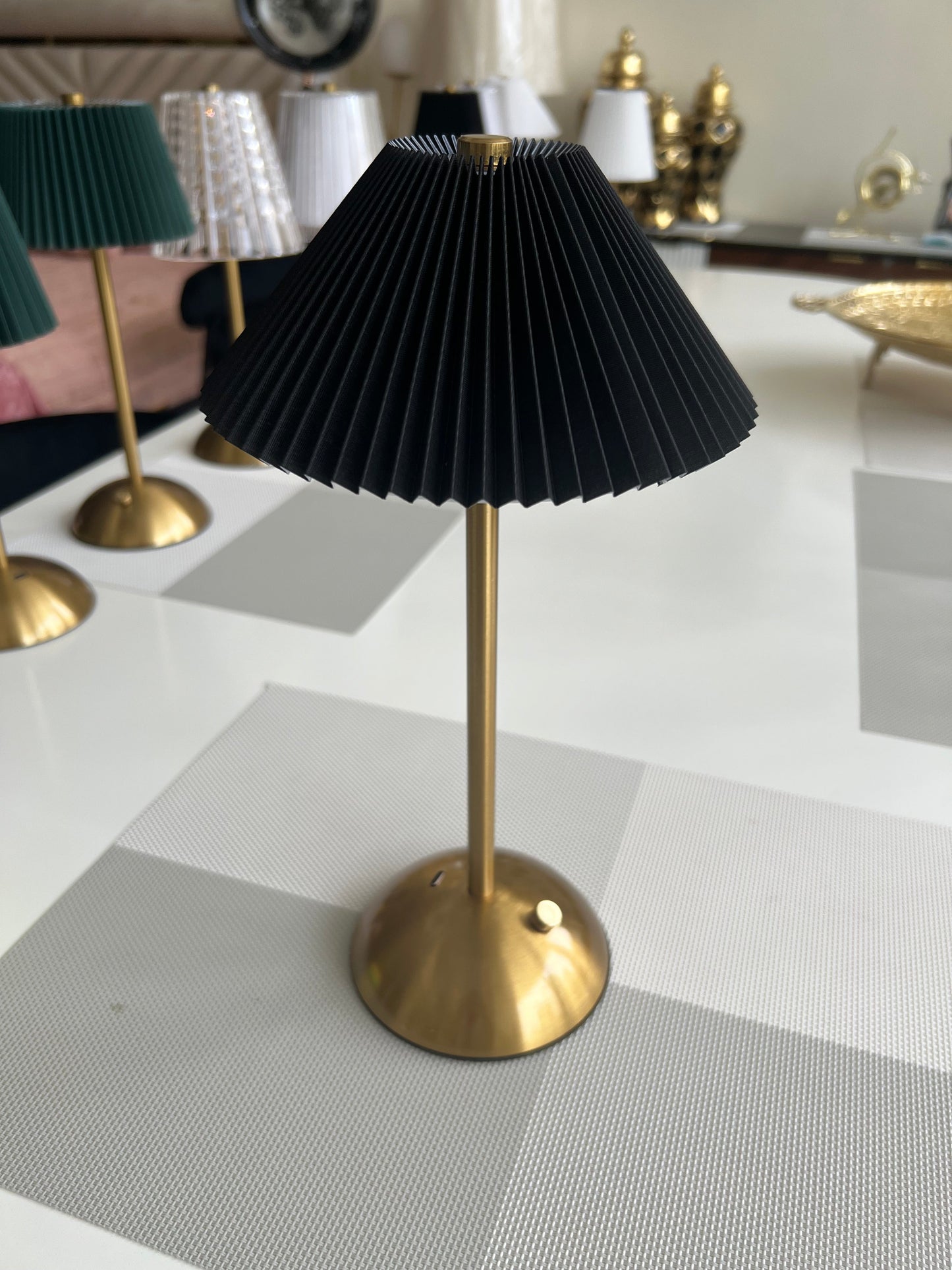 a table lamp with a pleated, cream-colored shade and a brass-toned base and stem.