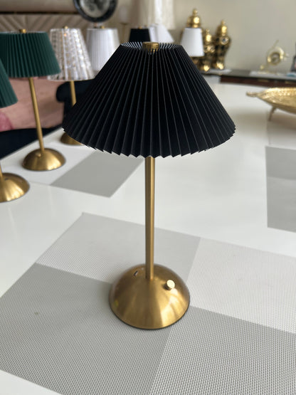 a table lamp with a pleated, cream-colored shade and a brass-toned base and stem.