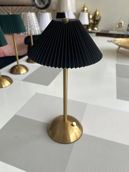 a table lamp with a pleated, cream-colored shade and a brass-toned base and stem.
